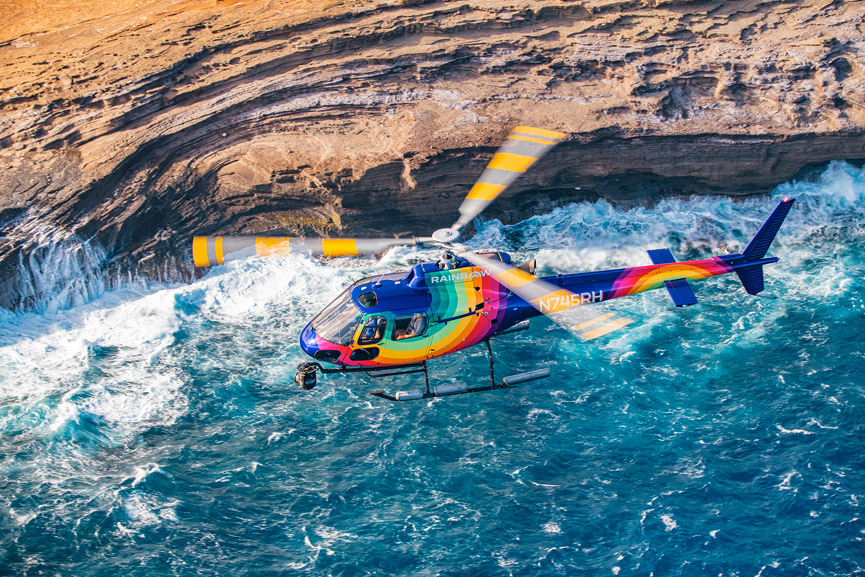 Rainbow Helicopters flying above crashing waves and jagged cliffs
