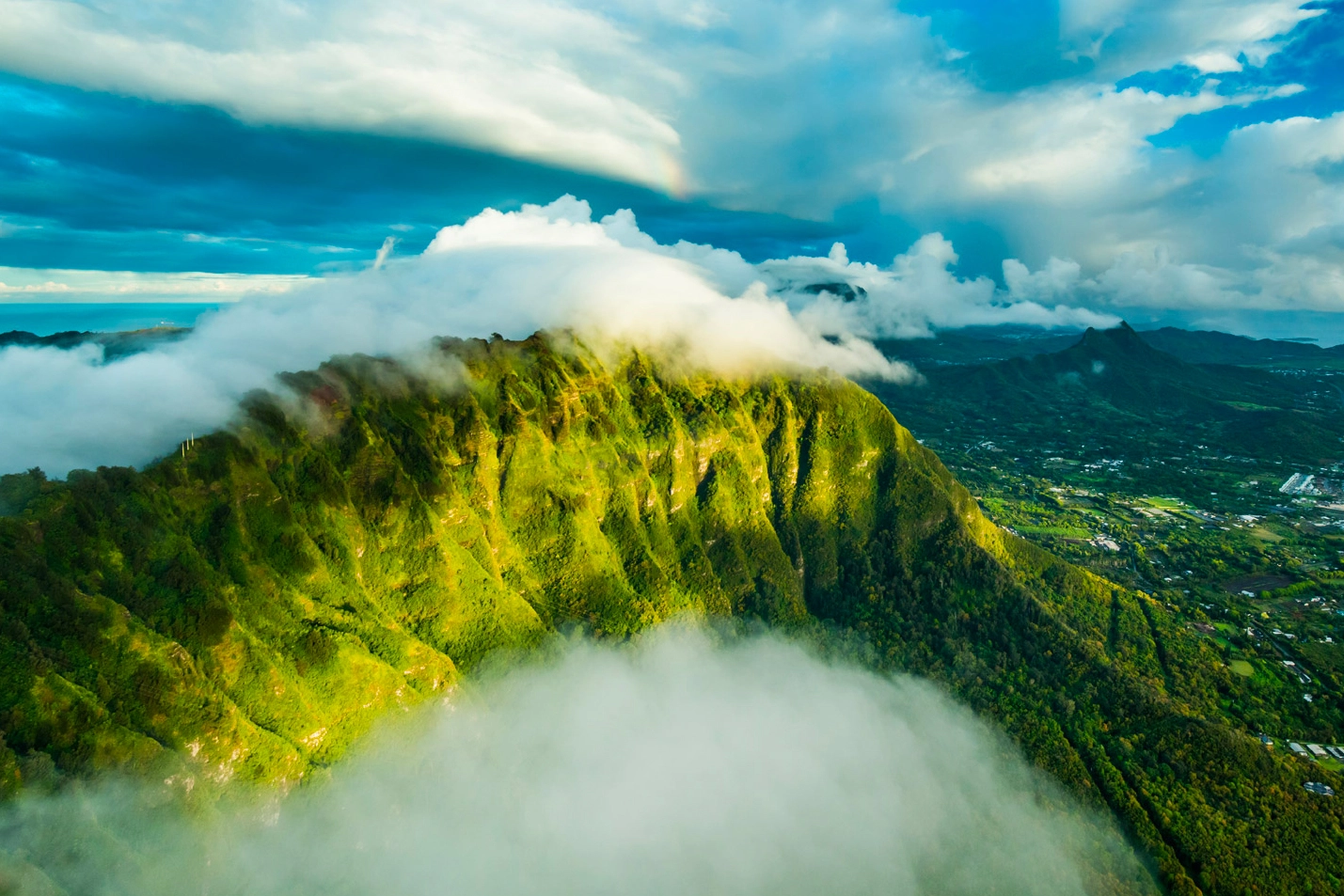 Green Hawaii mountain range covered in fog, aerial photograph of Oahu by helicopter