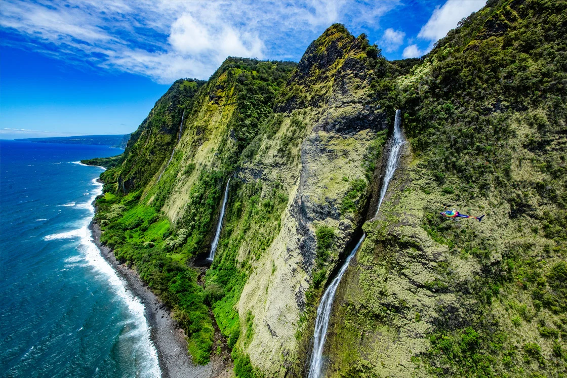 Hawaii Big Island Helicopter Tour. Rainbow Helicopter flying across Laupahoehoe Nui Falls on the Kohala Coast.