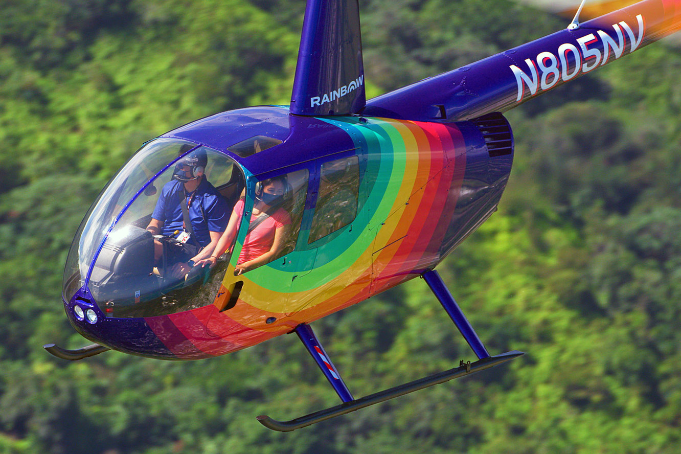 Rainbow Helicoptershelicopter flying above dense forest in Hawaii